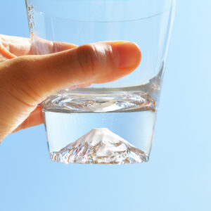 A clear glass with a sculpted Mt. Fuji design at the bottom, presented inside a wooden box.