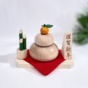 Handcrafted wooden Kagamimochi New Year decoration set featuring a beech wood rice cake, bamboo Kadomatsu, wooden sign, cypress tray, and red crepe cloth.