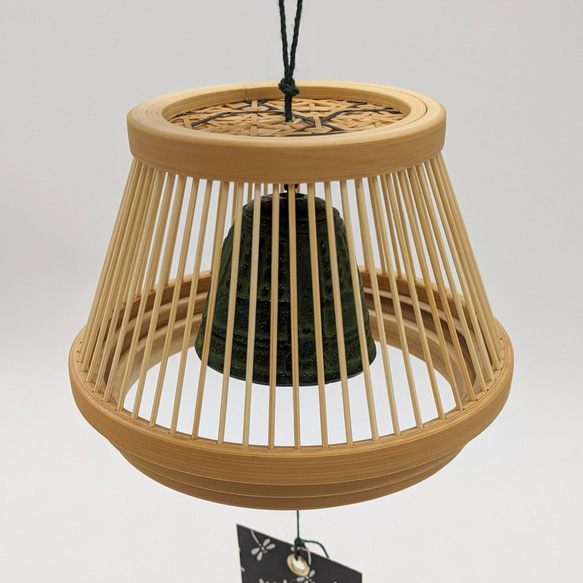 A conical Suruga bamboo lattice cage housing a dark Nambu iron wind bell, suspended from a tall tabletop wooden stand. – view 3