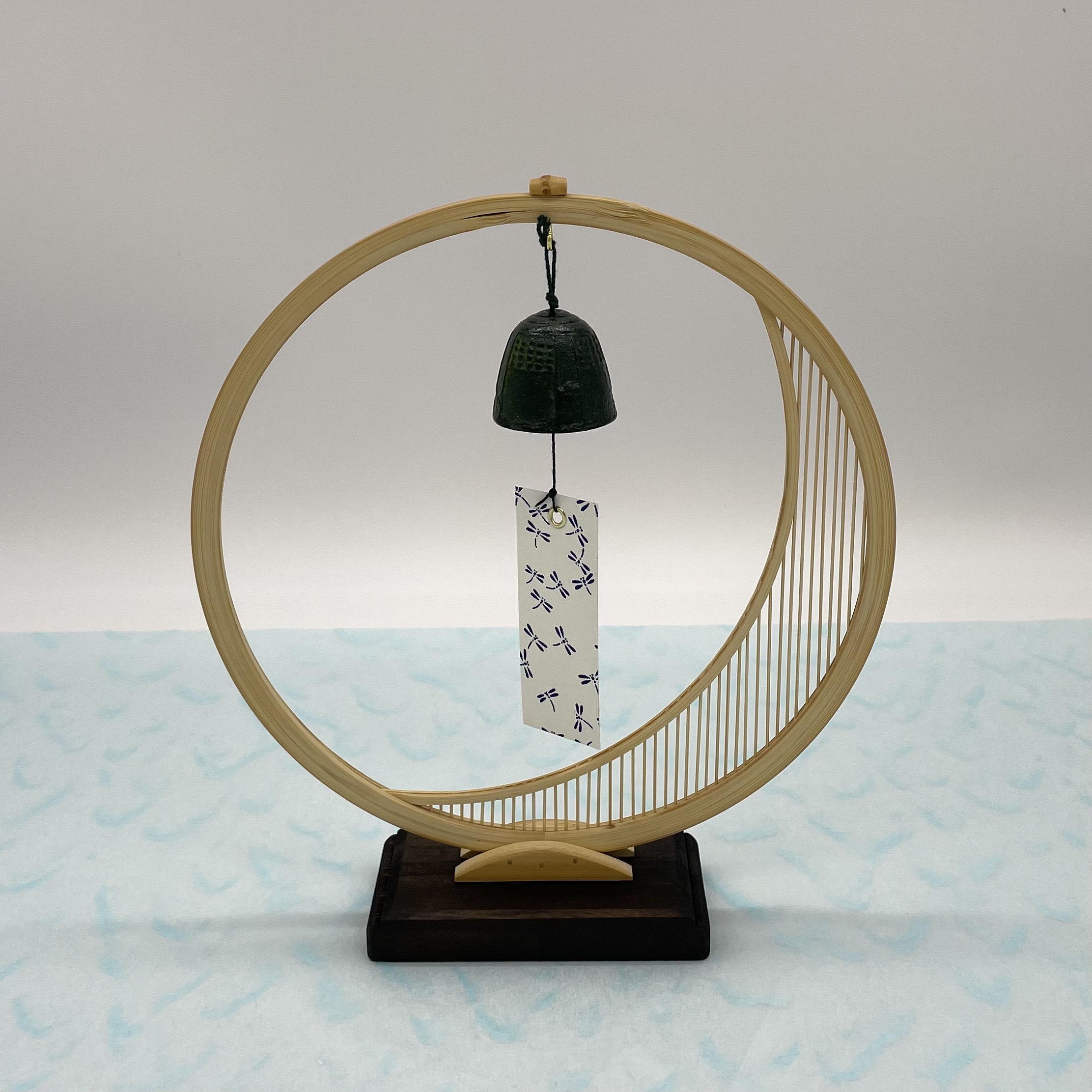 A delicate tabletop wind chime featuring a crescent moon-shaped Suruga bamboo frame holding a small dark Nambu cast iron bell