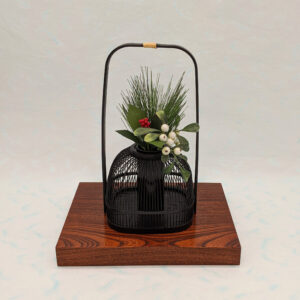 An elegant black Suruga bamboo flower vase with a rattan-wrapped handle, showcasing intricate vertical bamboo lattice work.