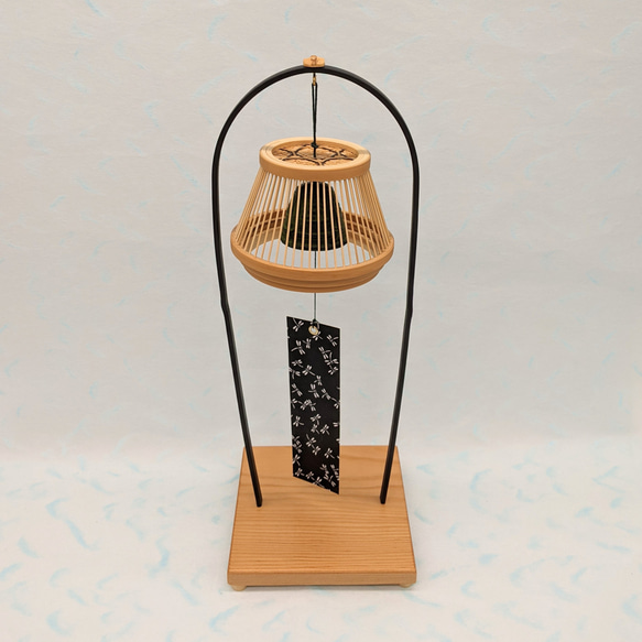 A conical Suruga bamboo lattice cage housing a dark Nambu iron wind bell, suspended from a tall tabletop wooden stand. – view 8