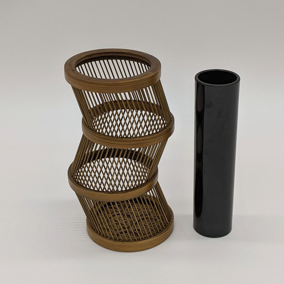 A hand-bent sepia Suruga bamboo single-flower vase with a unique undulating curve, intricate weaving at the base, and an accompanying dark wood stand. – view 5