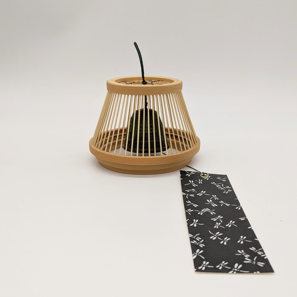 A conical Suruga bamboo lattice cage housing a dark Nambu iron wind bell, suspended from a tall tabletop wooden stand. – view 4