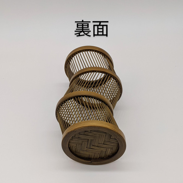 A hand-bent sepia Suruga bamboo single-flower vase with a unique undulating curve, intricate weaving at the base, and an accompanying dark wood stand. – view 6