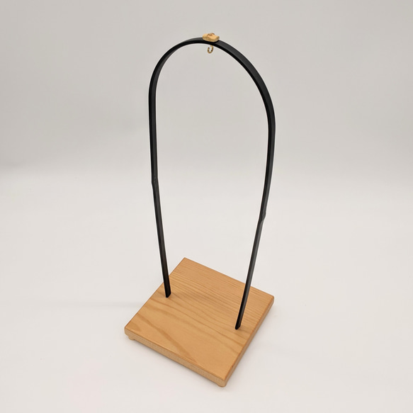 A conical Suruga bamboo lattice cage housing a dark Nambu iron wind bell, suspended from a tall tabletop wooden stand. – view 5
