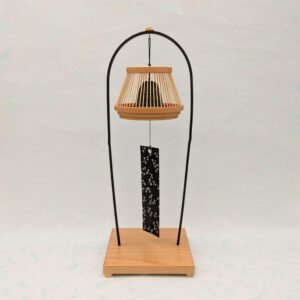 A conical Suruga bamboo lattice cage housing a dark Nambu iron wind bell, suspended from a tall tabletop wooden stand.